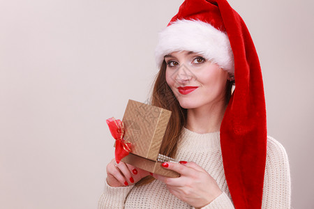 穿着圣达克萨斯帽子的开心女人金礼物盒带珍珠圣诞节时间赠与和幸福概念图片