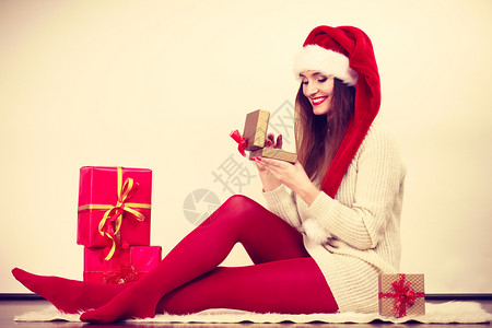圣诞冬季幸福概念身戴圣塔帮手帽子有许多红金礼物盒的妇女快乐做圣诞礼物图片