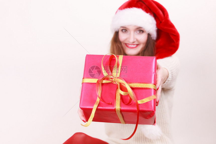 穿着圣达克萨斯帽子的漂亮女人拿着红色大礼物盒带丝圣诞幸福冬天和人的概念图片