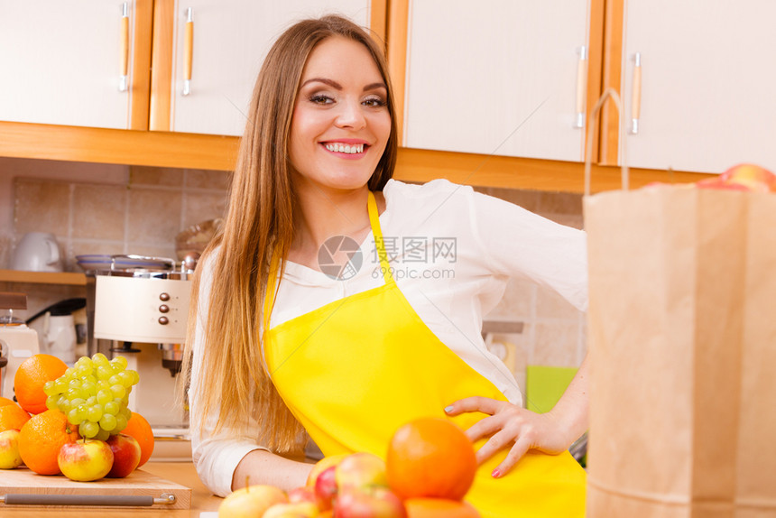 烹饪美食饮水果自然概念厨房的微笑女郎厨师靠在一堆水果和厨房用具旁边的柜台厨房微笑女郎图片