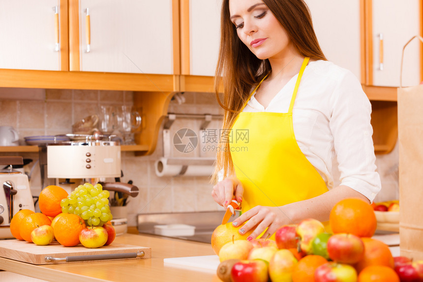 烹饪美食饮水果自然概念厨房的微笑女郎厨师靠在一堆水果和厨房用具旁边的柜台厨房微笑女郎图片