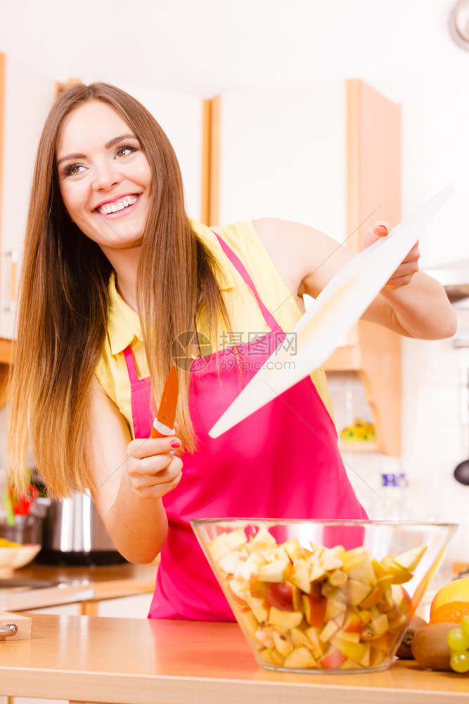 家庭厨房的年轻女家庭主妇在切苹果板上把水扔进碗里健康饮食烹饪素饮和人的概念图片