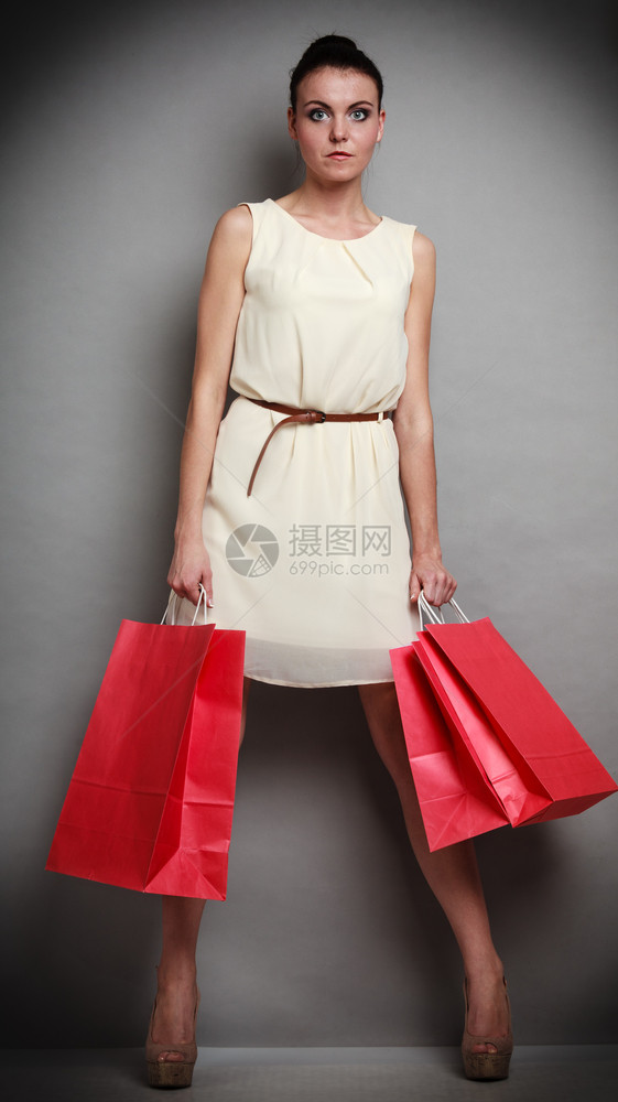 销售和零概念高雅的时装女郎全身穿着红色购物袋手握着工作室灰色背景的红袋图片