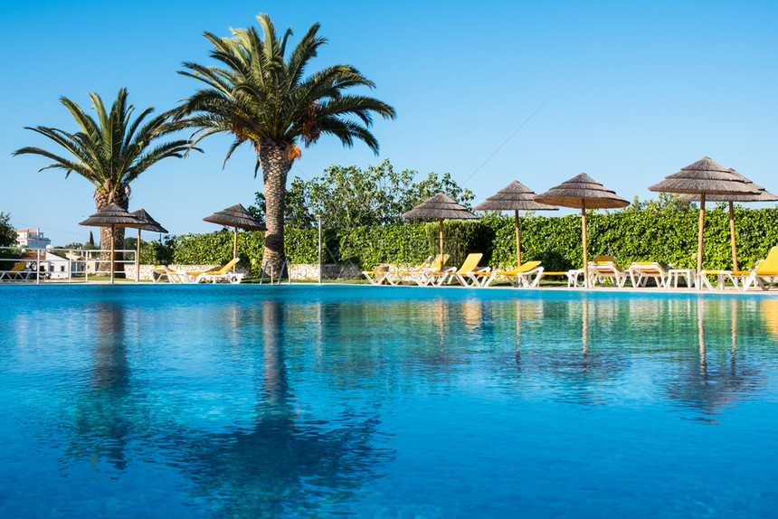 美丽的热带海滩前旅馆度假胜地有游泳池雨伞阳光和棕榈树明媚的一天堂度假目的地美丽热带海滩前旅馆度假胜地阳光明媚的一天图片
