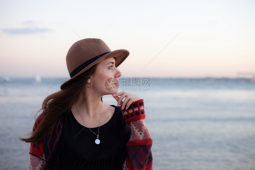 穿旅行服装和戴帽子的妇女坐着看蓝海和天空旅行概念照片坐着和看蓝海天空的妇女图片