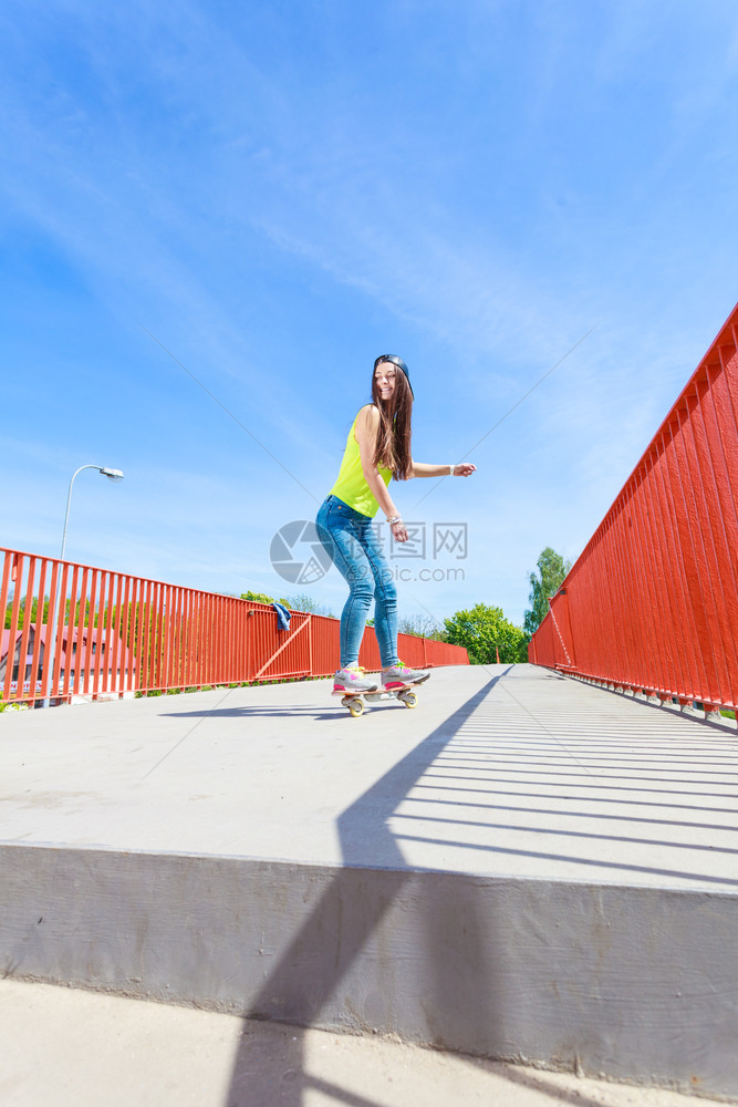 玩暑期运动和积极生活方式穿着全身滑板的酷少女在街上玩滑板外面图片