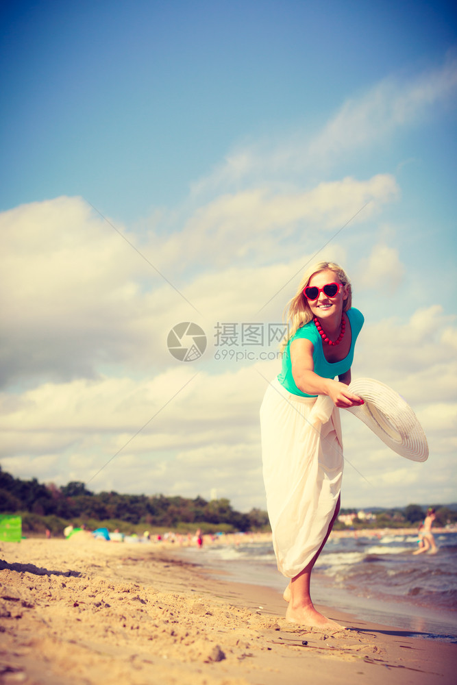 沙滩上迷人的女戴墨镜士玩帽子得开心海滩上迷人的女图片