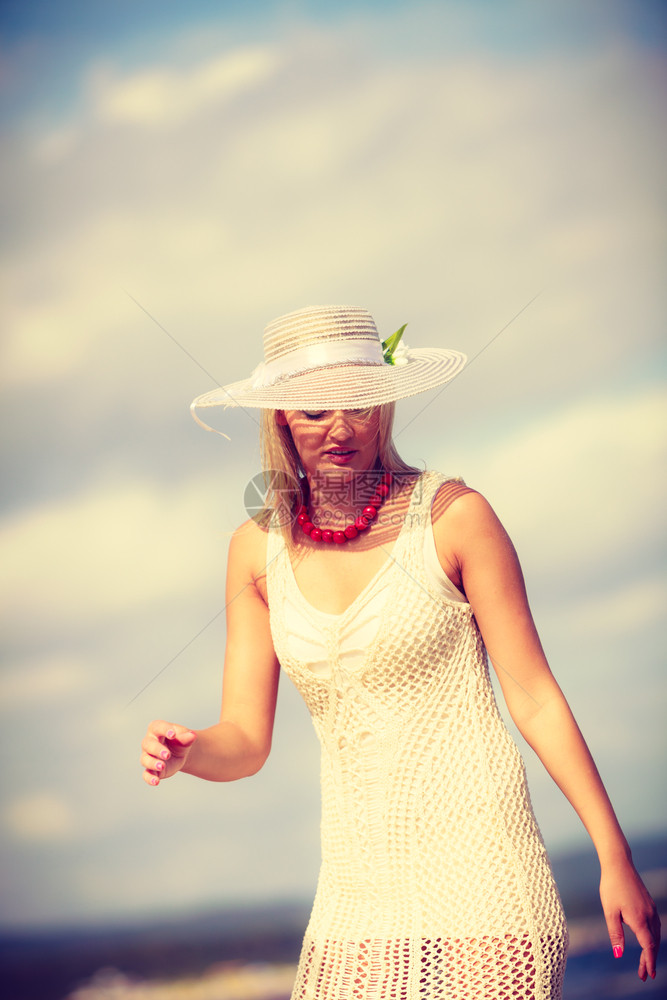 穿着白裙子和戴太阳帽的美丽金发女子肖像图片