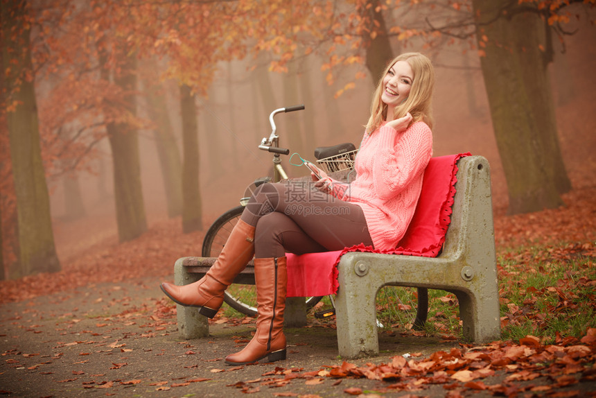 年轻女子靠在自行车边坐着休息图片