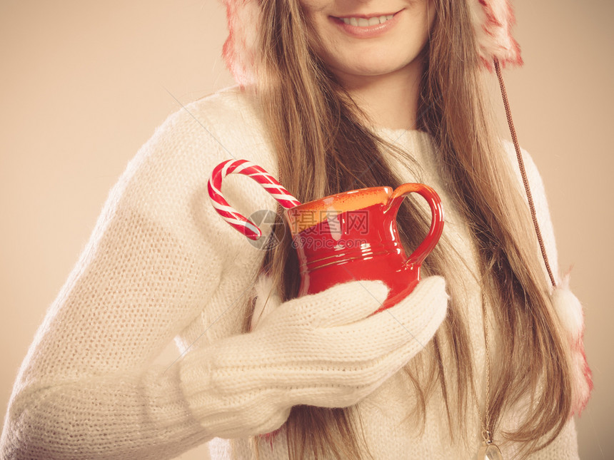 年轻女士拿着糖果棒杯女孩拿着羊毛白手套圣诞节时间概念用甘蔗杯女孩们拿着羊毛白手套圣诞节时间概念图片