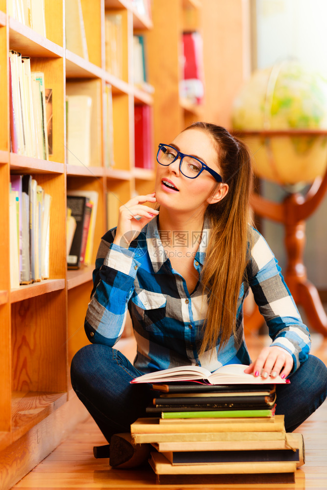 教育学校概念聪明的女学生长发孩蓝色眼镜坐在有书本的大学图馆地板上图片