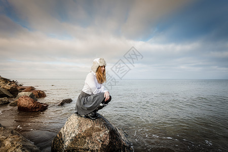 美丽的海边景色概念岩石阴云天的海平面女人看着美丽的风景图片