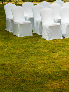 许多张白色优雅封面的婚礼椅子绿色草地上有许多张白色优雅封面的婚礼椅子门外拍摄背景图片
