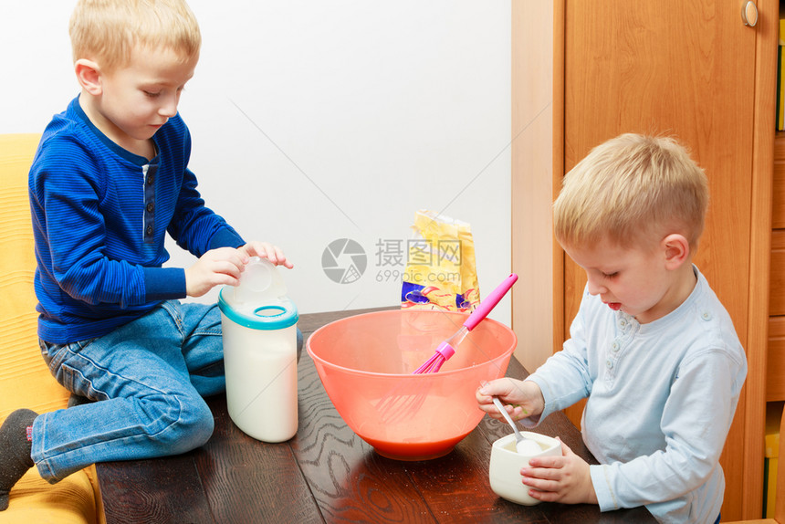 两个男孩在碗里做蛋糕图片