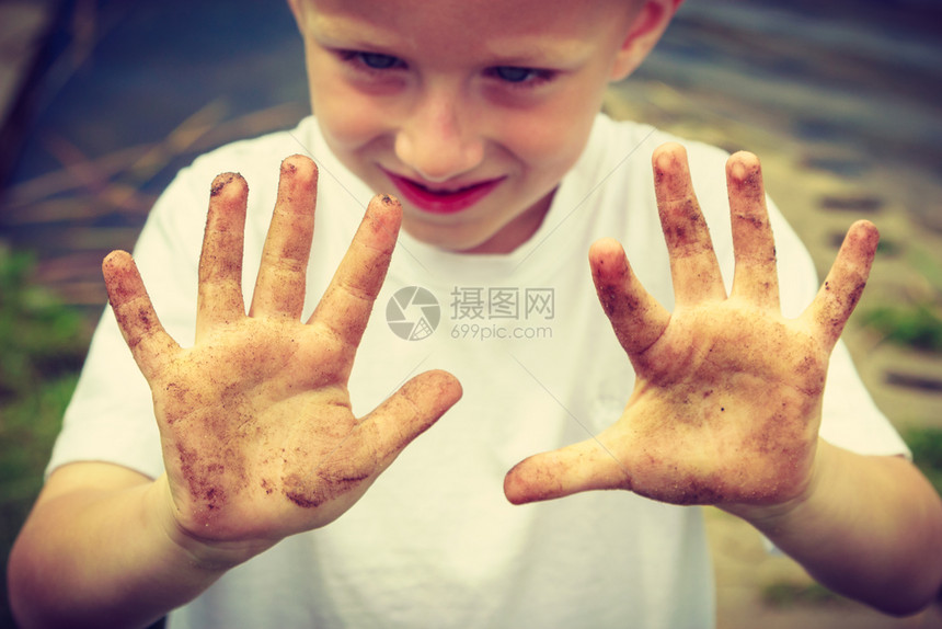 小男孩举着肮脏的泥巴手图片