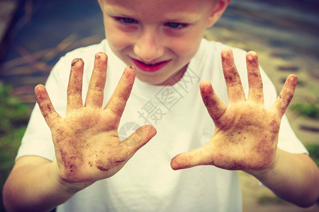 小男孩举着肮脏的泥巴手图片