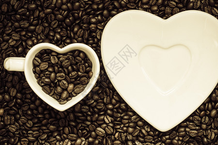 咖啡时间白色杯子和茶碟以烤咖啡豆背景为心形的白杯子和碟图片
