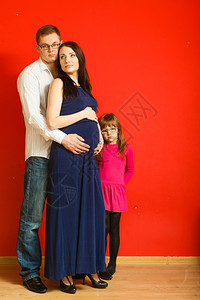 孕妇男人和女儿在红色背景上图片