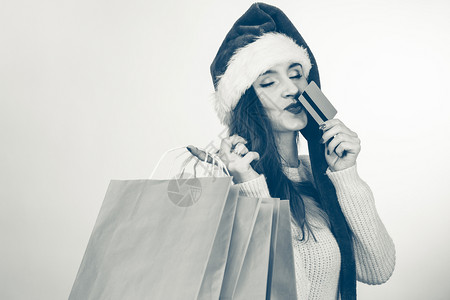 圣诞购物的快乐女孩穿着圣塔帽袋的年轻快乐女人节日庆祝商业快乐休闲概念图片
