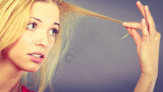 忧郁的金发看着被毁坏的头发灰色背景悲伤的女子看着被毁坏的头发图片