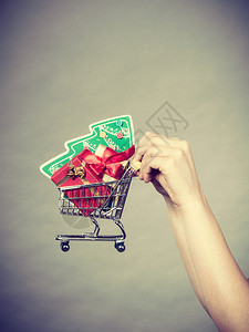 圣诞节季节销售冬庆祝活动概念妇女手拿着购物车篮子里面有小圣诞树和礼物背景图片