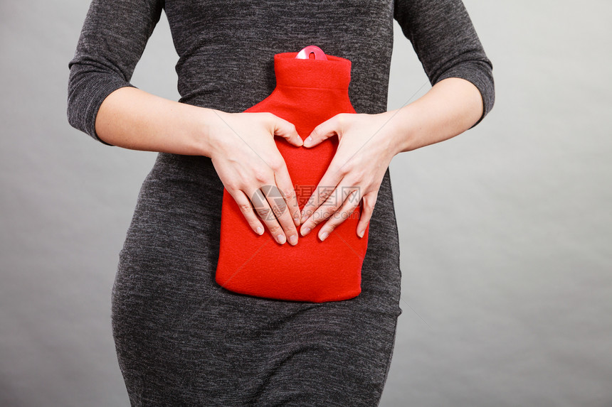 女腹痛将热红水瓶放在腹部作为治疗疼痛的药方用双手塑造心脏形状卫生保健女孩将热水瓶放在腹部用手塑造心脏形状图片