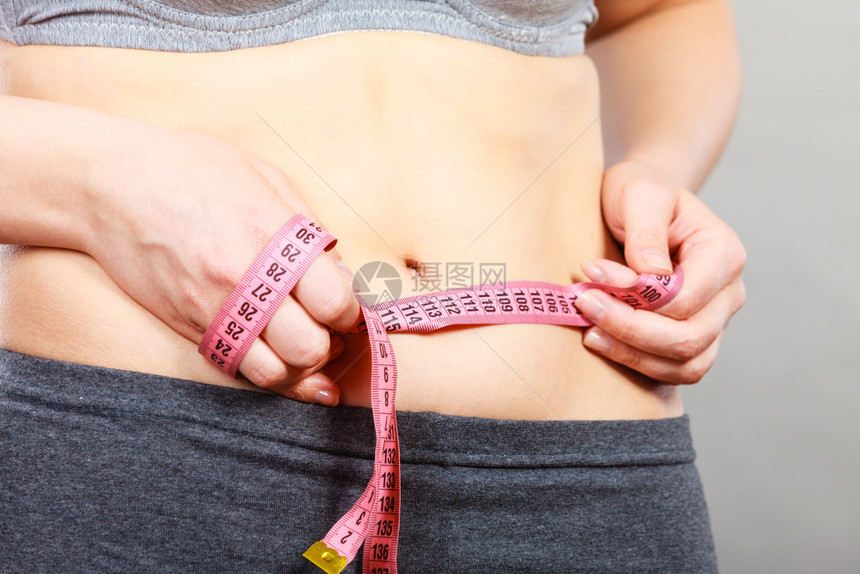 消除腹部脂肪饮食体重减肥或增的概念触摸胃妇女拿着测量胶带抚摸胃的妇女拿着测量胶带图片