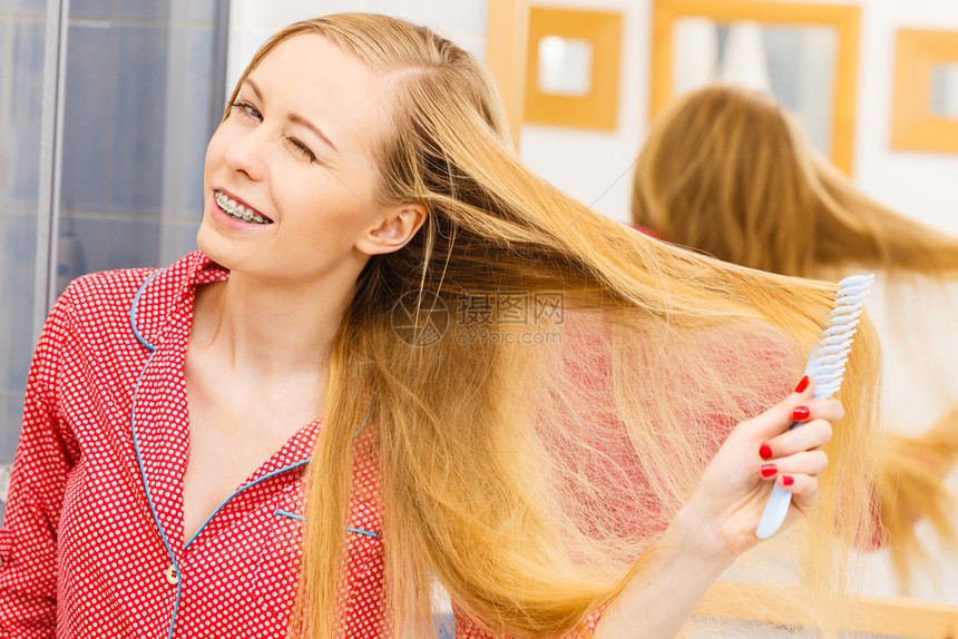 女人在浴室梳她的长发看着镜子女孩在照顾下刷新发型理概念女人在浴室梳她的长发图片