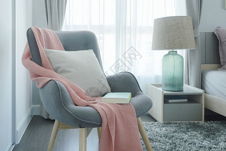 睡在卧室的床边有粉色围巾枕头和书的灰色手椅粉围巾枕头和书图片