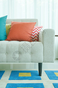 沙发上的橙色和绿枕头带有图形型地毯图片