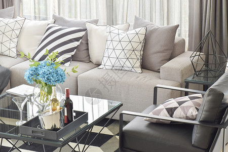 灰色沙发的混合型枕头和客厅中桌的酒瓶背景