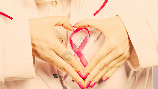 做慈善关紧女医生的手会用粉色丝带符号做心脏帮助和慈善过滤手心会用粉色丝带符号做心脏背景