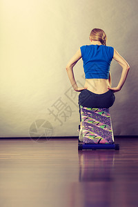 年轻少女在长椅上接受培训以便在家里坐下来身体健康胃肌肉锻炼图片