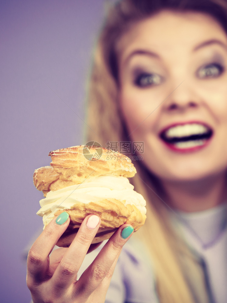 甜美的食物和快乐概念有趣是快乐金发女人拿着美味的巧克力蛋糕奶油兴奋的疯狂面容表情在紫罗兰上有趣的女人拿着奶油蛋糕图片