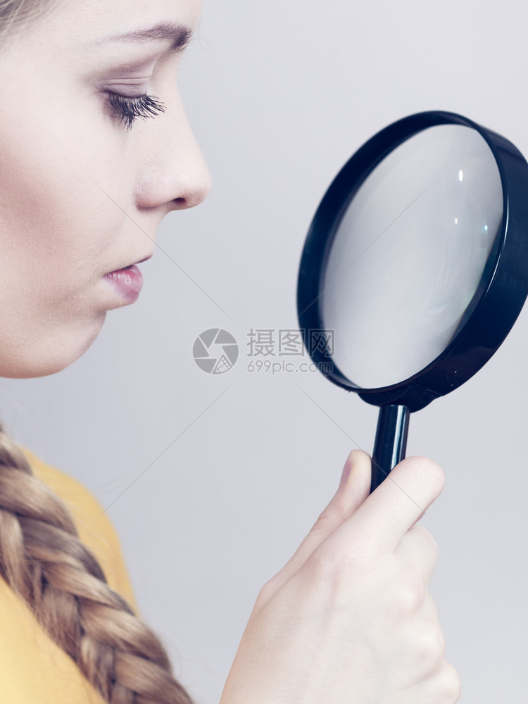 金发女人拿着放大镜调查某事仔细看一试图找到解决方案图片