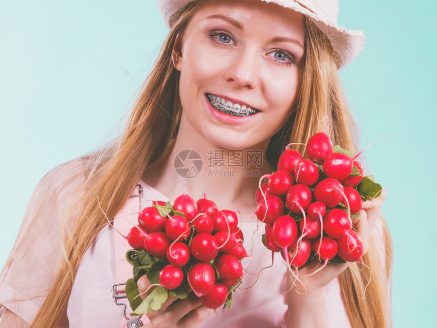 快乐的年轻少女准备过暑假穿粉红色的衣服戴太阳帽展示美味的萝卜图片