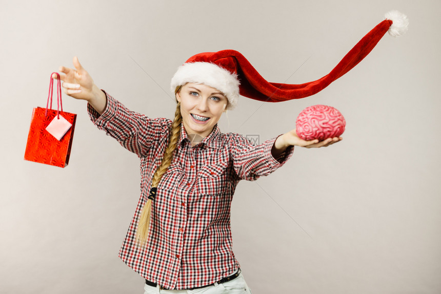 穿着风吹的圣诞老人帮手帽子书包和假大脑的快乐妇女图片