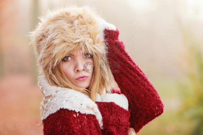 在秋天森林公园的漂亮女人穿着毛皮冬帽和衣的漂亮年轻女孩穿着毛皮冬帽和衣秋天时尚穿着毛皮冬帽的漂亮时尚女人图片