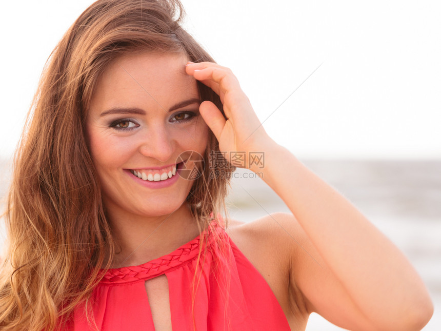 美丽的笑容女孩长发在风中吹着海滩上迷人的时尚女郎图片
