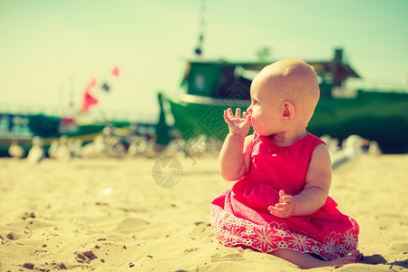 小孩在海滩上快乐的玩嘴里含着手图片