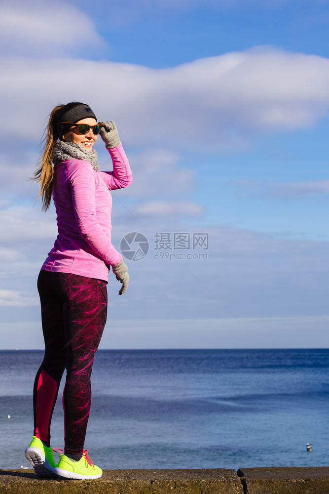 女子在户外运动后休息健身女运动员在寒冷的天气中穿着温暖运动服在海边休息女子在寒冷的户外运动后休息图片