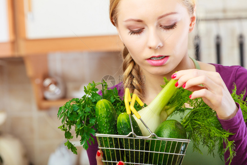 购买健康的饮食品概念厨房里的妇女有许多绿色蔬菜手持小购物篮车厨房里的妇女手持蔬菜篮子厨房里的妇女手持蔬菜篮子图片