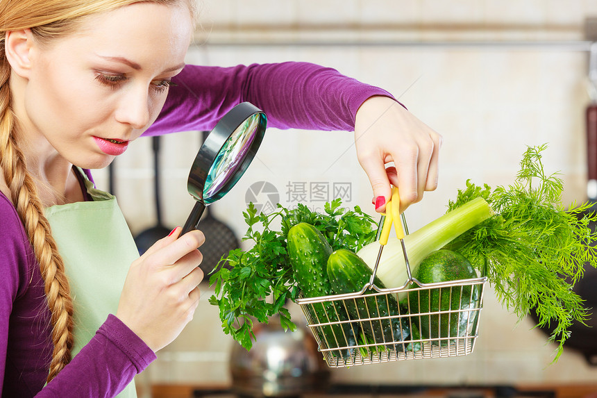 购买健康的饮食品概念厨房里的女人有很多绿色蔬菜她们通过放大镜看购物篮小车女人通过放大镜看蔬菜篮图片