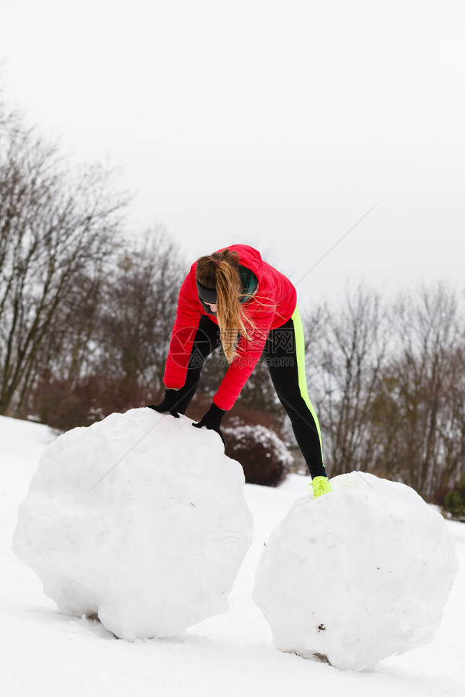 穿着温暖运动服的妇女冬季在户外锻炼做雪人时玩得开心穿着运动服的妇女冬季锻炼穿着运动服的妇女冬季运动图片
