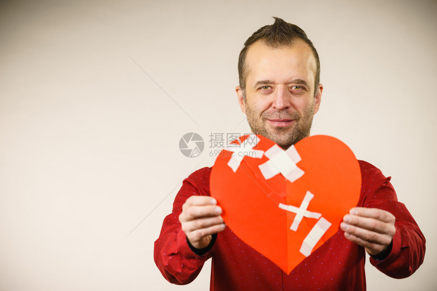 治愈的爱情人节概念笑着的成年人用石膏拿着红心的成年人男愈合关系图片
