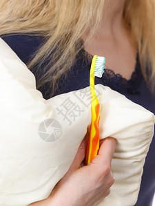 手持白枕头和橙牙刷浴室口腔卫生用具概念手持牙刷和枕头的人图片