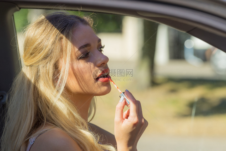 年轻有吸引力的女士在开车时用唇膏化妆女在车上用唇膏涂图片