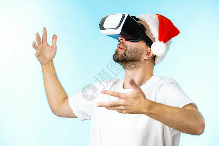穿着圣达克拉斯帽的人带着虚拟真实的护目镜头盔探索太空网络圣诞节概念图片