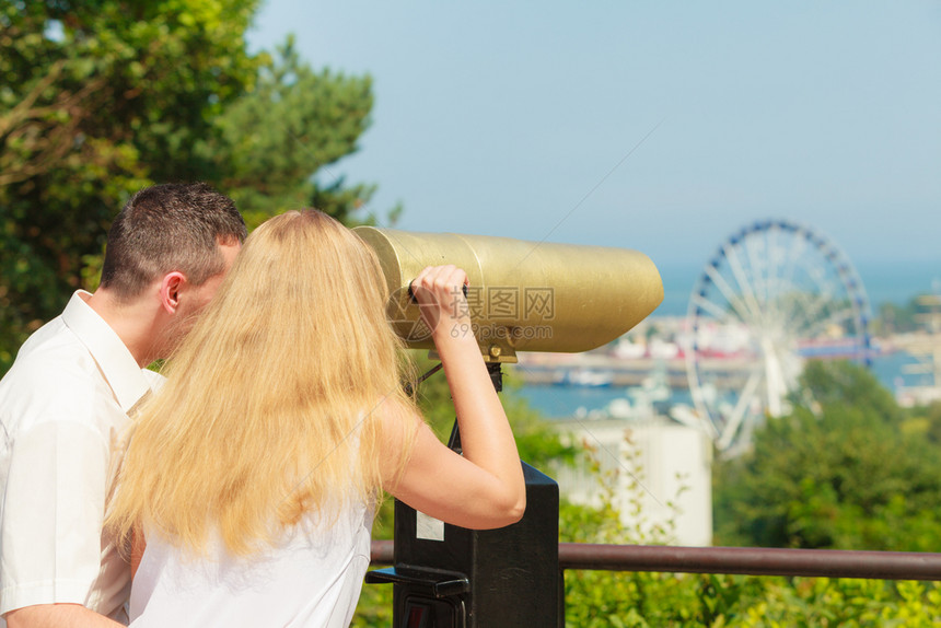 男人和金发女通过城市望远镜一起观光幸福的情侣通过城市望远镜图片