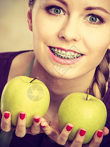 长头发的年轻女子持有两个大绿色黄苹果水健康饮食素和人的概念图片